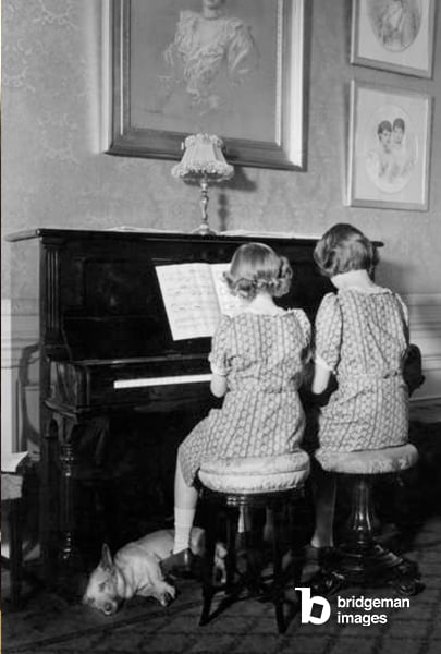 la principessa Elisabetta e la principessa Margaret che suonano il pianoforte, il cane Jane ai loro piedi, al castello di Windsor, 22 giugno 1940 © Collection Gregoire  Bridgeman Images